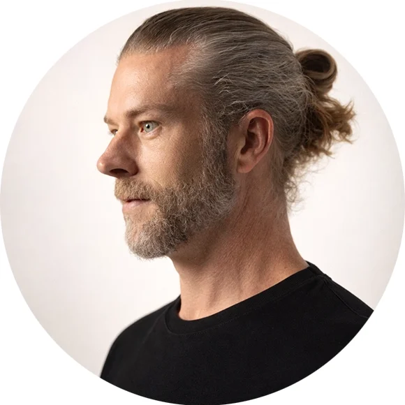 Paul Talley Masseur bei HannoverMassage Paul Talley mit grauem Bart und Zopf, in Profilansicht, trägt ein schwarzes T-Shirt.